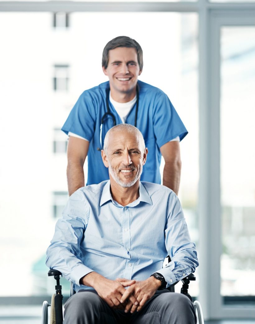 Portrait of a male nurse caring for a senior patient in a wheelchair.
